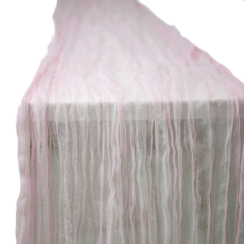 A gauze table runner in dusty pink, featuring a soft and airy fabric. The subtle dusty pink color adds a vintage and elegant touch to any table setting, perfect for enhancing a chic and charming ambiance.