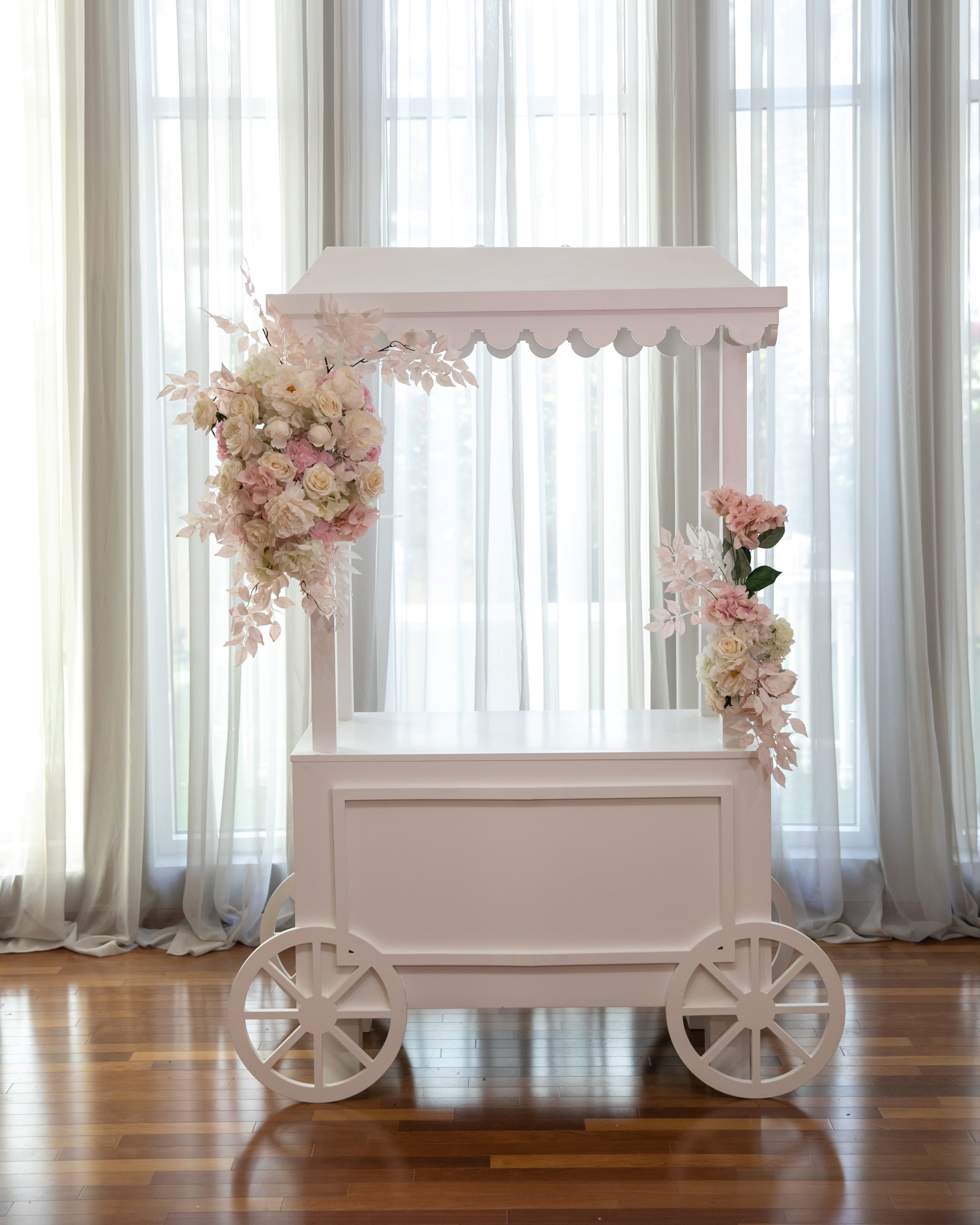A white dessert cart, featuring a sleek and elegant design with multiple tiers for showcasing sweets and treats. The cart&