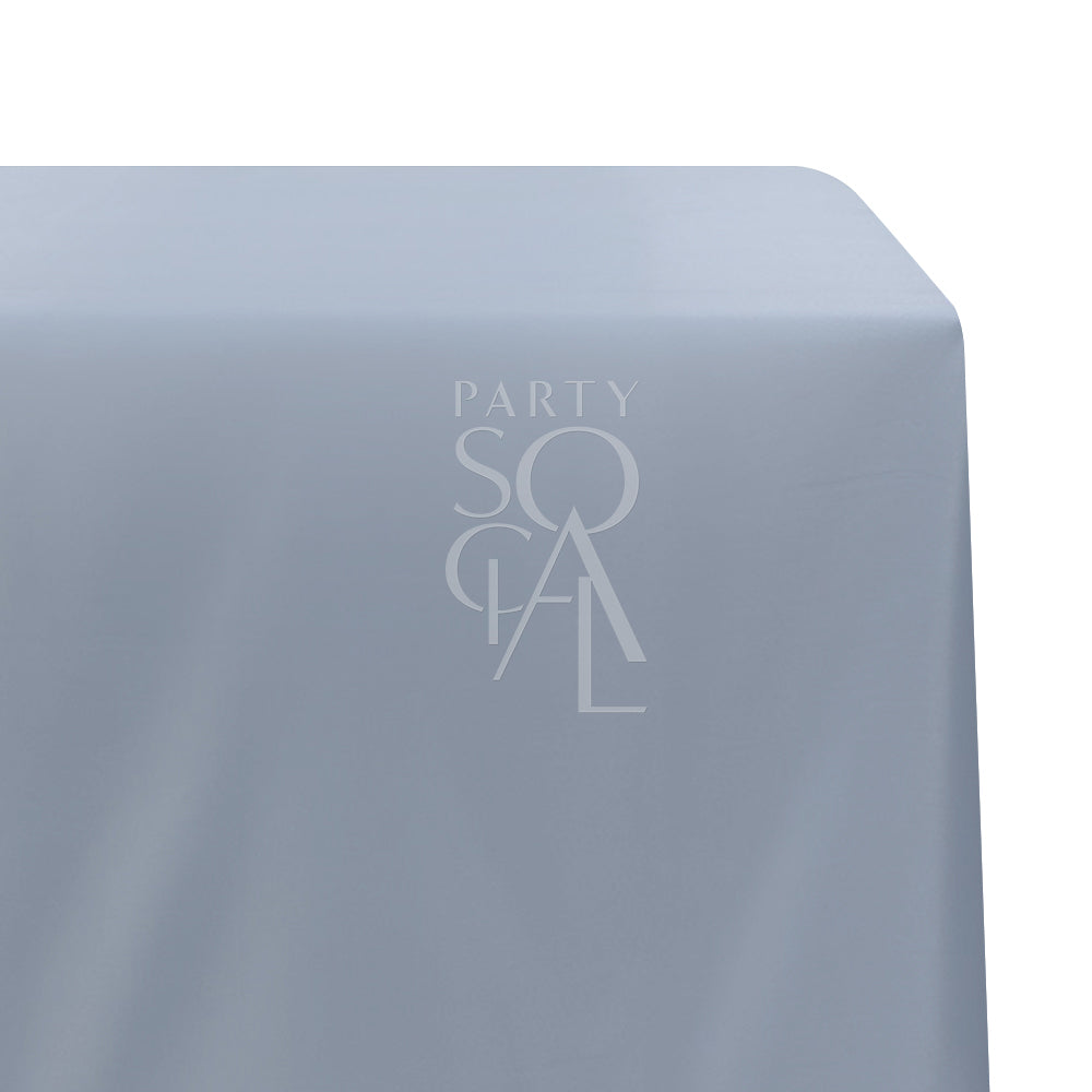 A rectangular satin tablecloth in muted dusty blue, featuring a refined and glossy finish. This elegant tablecloth adds a touch of sophistication and tranquility to your dining setting, perfect for formal events and modern gatherings.