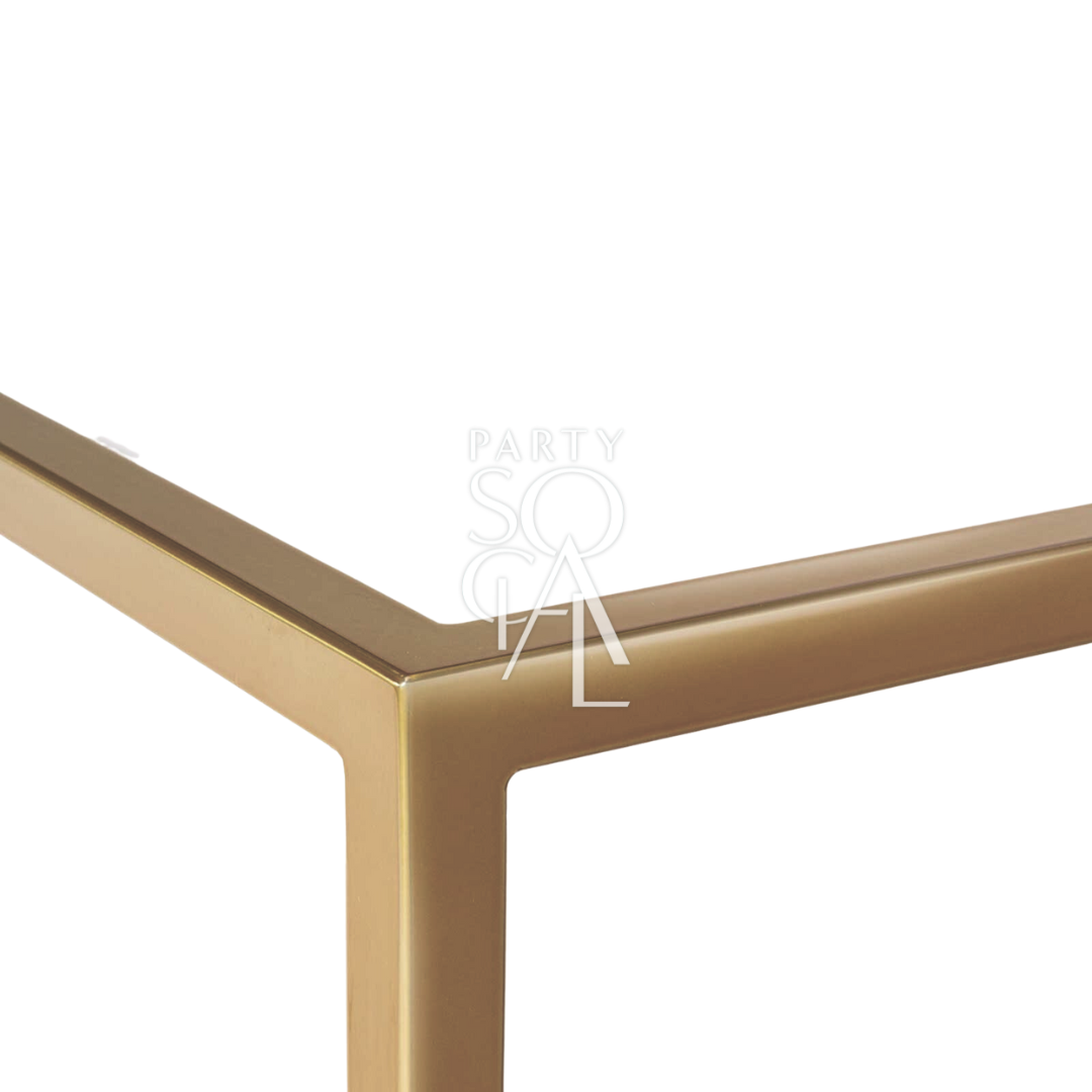 A high glass rectangular table with a gold base, featuring a sleek and modern design with a clear glass tabletop and a sturdy gold-finished base. The combination of transparent glass and luxurious gold provides a sophisticated and contemporary look, perfect for dining rooms, conference rooms, or stylish event settings.