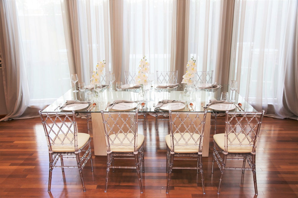 Modern glass dining table featuring a sleek, transparent tabletop supported by a sturdy, minimalist base. The clear glass surface enhances the table’s elegant design, making it a versatile and stylish choice for contemporary dining spaces and modern interiors.