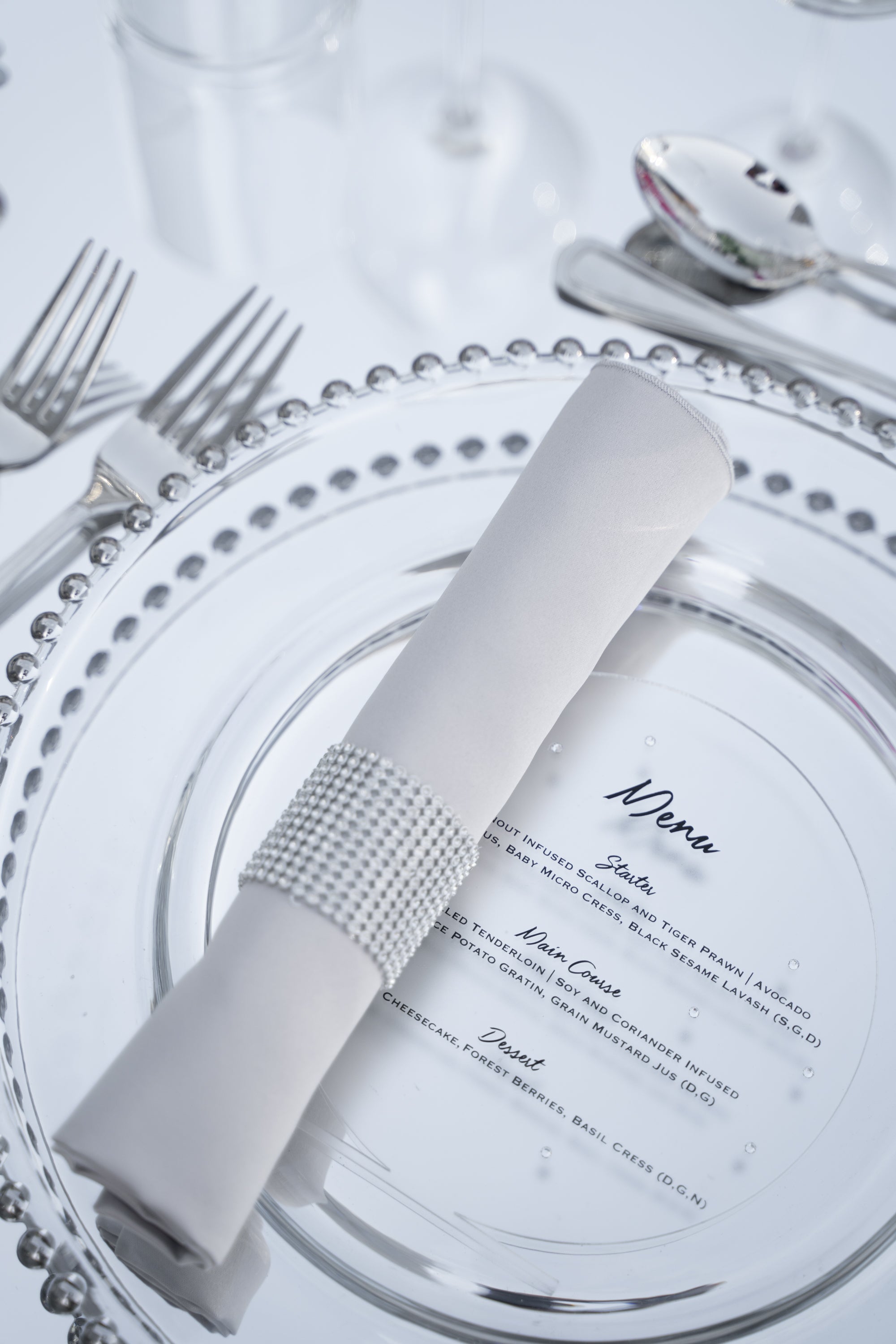 A diamante round napkin ring featuring a sparkling and elegant design. This napkin ring is adorned with clear, faceted diamante stones arranged in a round pattern, adding a touch of glamour and sophistication to any table setting. Perfect for formal dinners, special occasions, or adding a luxurious detail to your table decor.