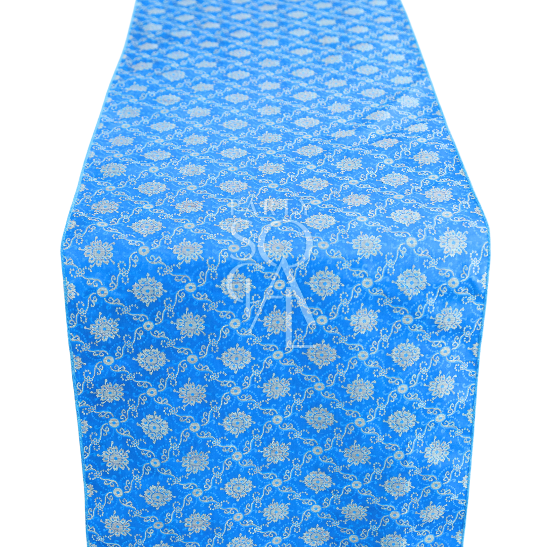 A cushion cover in blue brocade, featuring a luxurious pattern with intricate textures and elegant detailing. This cover adds a sophisticated touch to any decor, perfect for enhancing sofas, chairs, or beds.