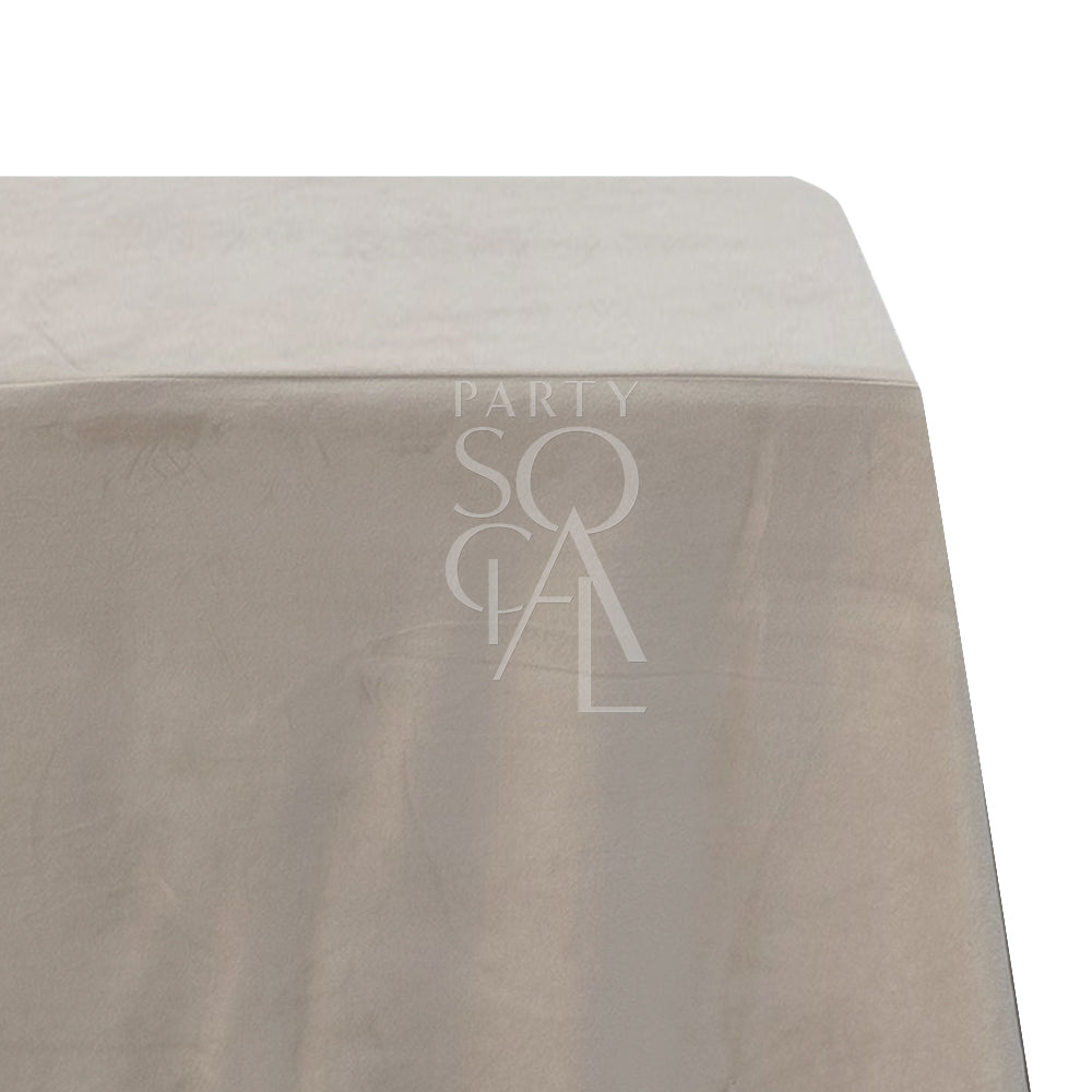 A rectangular velvet tablecloth in a sandy beige color, crafted from a cotton/linen blend. This stylish tablecloth enhances your decor with its rich, velvety texture and neutral tone, ideal for both casual and formal settings.