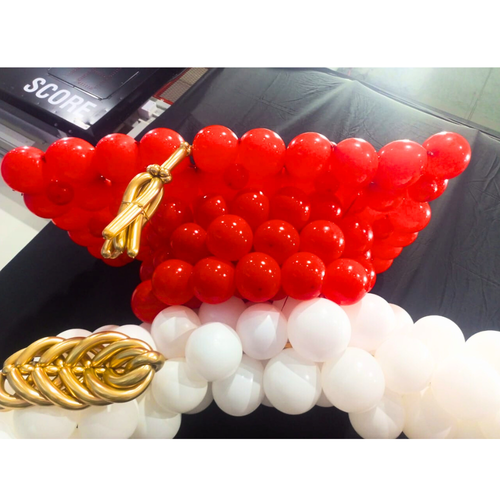 A graduation cap round balloon arch in white and red, featuring a celebratory and vibrant design. Made from durable plastic and metal, this arch adds a festive touch to graduation parties and ceremonies, creating a striking visual centerpiece.