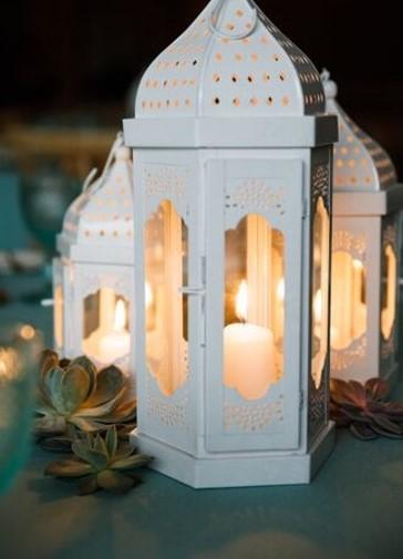 Elegant white Moroccan lanterns with intricate cut-out patterns, featuring a delicate design and soft white finish, adding a touch of exotic charm and sophistication to any space.