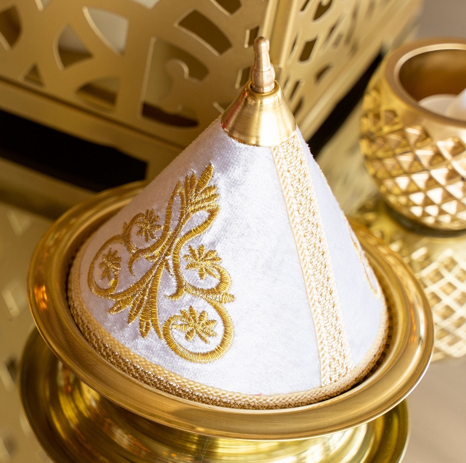 Traditional white Arabic tajine with a conical lid, showcasing intricate designs. Available for rent, it adds a touch of authenticity to any setting.