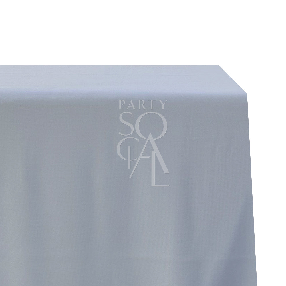 A rectangular cotton-linen tablecloth in muted dusty blue, featuring a soft and serene color. This stylish tablecloth adds a touch of subtle elegance and tranquility to your dining area, perfect for both special events and everyday use.