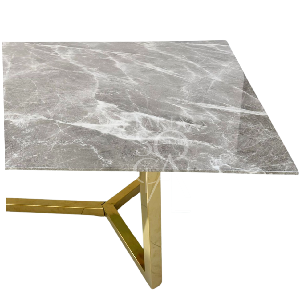 A table with a gold base and a grey marble top, featuring a luxurious and modern design. The gold base provides a striking contrast to the sophisticated grey marble top, creating an elegant and stylish centerpiece. This table enhances any decor with its refined and opulent look.