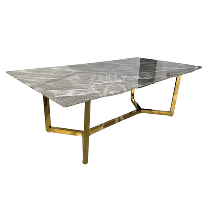A table with a gold base and a grey marble top, featuring a luxurious and modern design. The gold base provides a striking contrast to the sophisticated grey marble top, creating an elegant and stylish centerpiece. This table enhances any decor with its refined and opulent look.