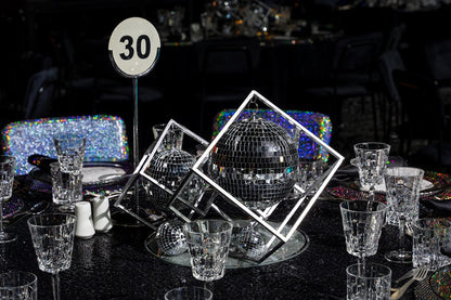 A round centerpiece in silver dust, made from glass. The silver color adds a touch of elegance and sophistication, while the glass material provides a sleek and reflective finish. This stylish centerpiece enhances any table setting with its luxurious and modern look.