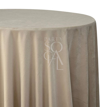 A round velvet tablecloth in soft sand, featuring a luxurious and plush texture. This elegant tablecloth adds a touch of warmth and sophistication to your dining area, perfect for both casual and formal settings.