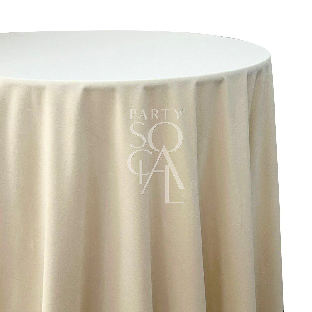 A round velvet tablecloth in creamy off-white, with a smooth and opulent finish. This refined tablecloth enhances your dining area with its elegant texture and classic color, ideal for special occasions and stylish gatherings.