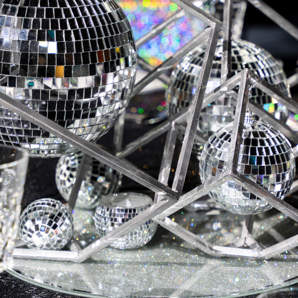 A silver Disco Ball Candle Holder featuring a playful and stylish mirrored design. This unique candle holder adds a touch of retro glamour and sparkle to any table setting or decor. Ideal for parties, events, and themed celebrations, it reflects light beautifully and enhances the atmosphere with its eye-catching and festive appearance.