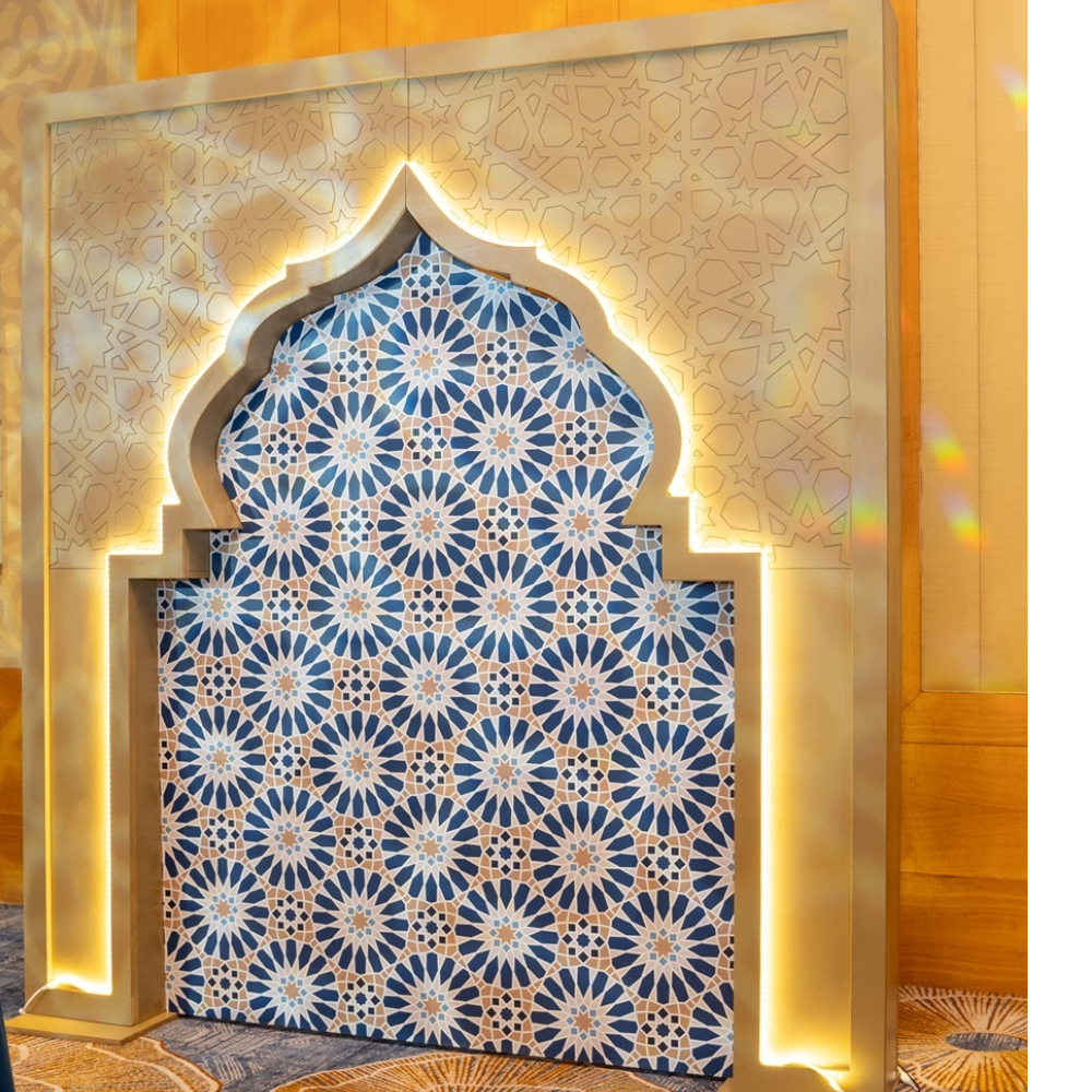 A beautifully designed Arabic-style arch featuring ornate patterns and glowing LED lights, offered for rent. The arch is lit with a warm, inviting glow, highlighting its intricate details and elegant curves.