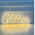 A "Glitter" LED neon sign in white, featuring a bright and elegant design. AC powered, this sleek sign is suitable for indoor use, perfect for adding a touch of sparkle and sophistication to parties, events, and home decor.