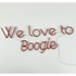 A "We Love To Boogie" LED neon sign in red, featuring a bold and vibrant design. This eye-catching sign is suitable for indoor use, adding a fun and energetic touch to parties, events, or home decor with its lively and nostalgic vibe.