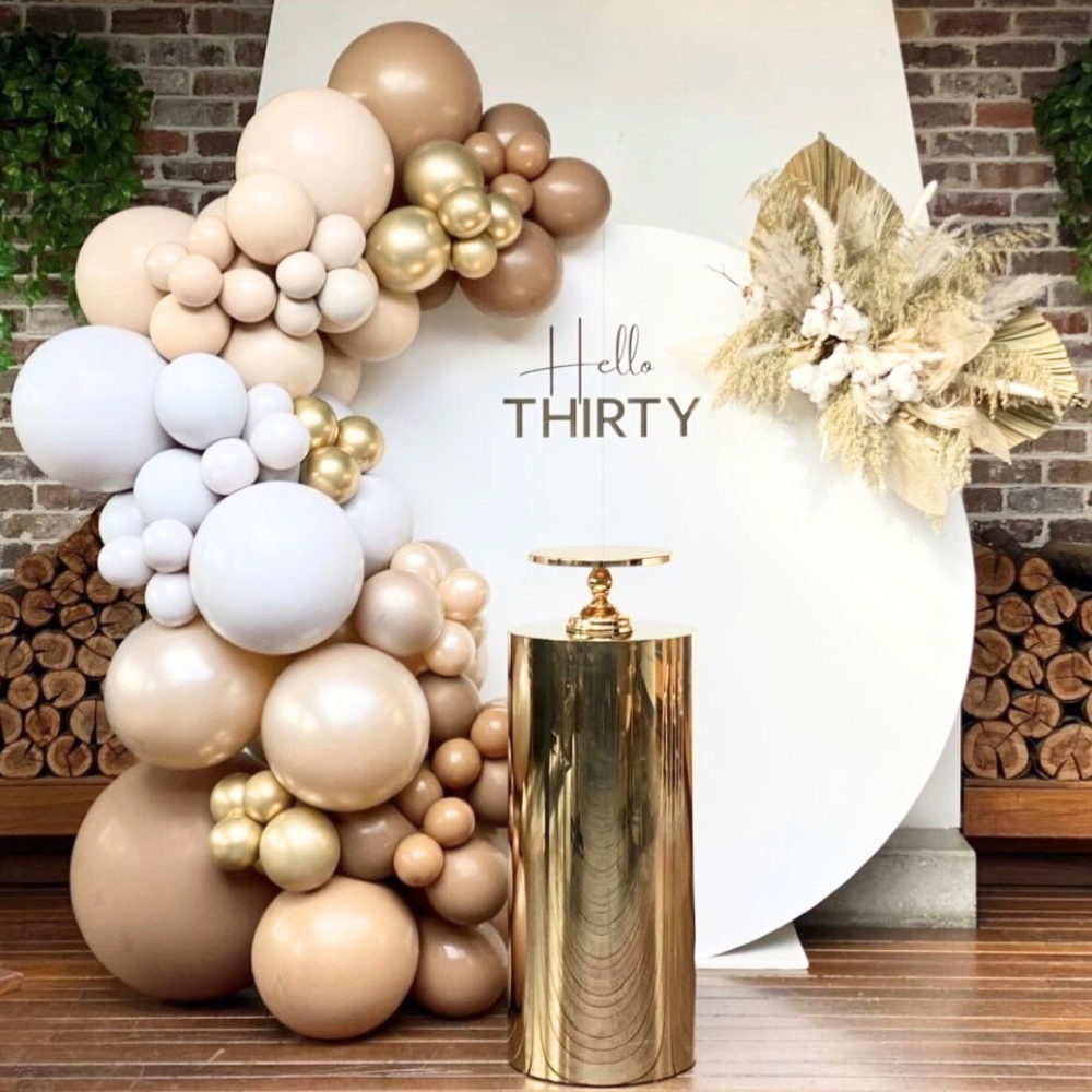 A round podium with a gold finish, featuring a balloon backdrop. The podium is made of wood with a gold sheen, while the balloon backdrop includes gold-colored balloons, creating a luxurious and festive design. This setup adds a touch of elegance and celebration to any event, perfect for enhancing decorations and creating a striking visual impact.